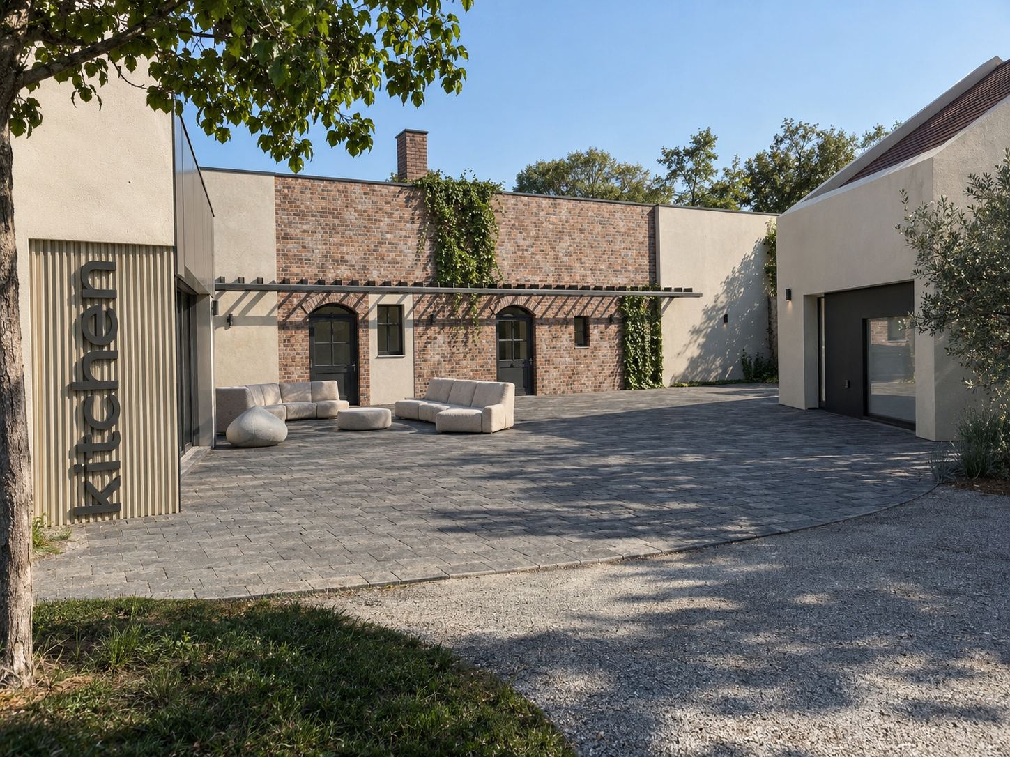 Paved arrival courtyard with the shared kitchen building and the restored brick cellar façade with its vine-covered wall behind